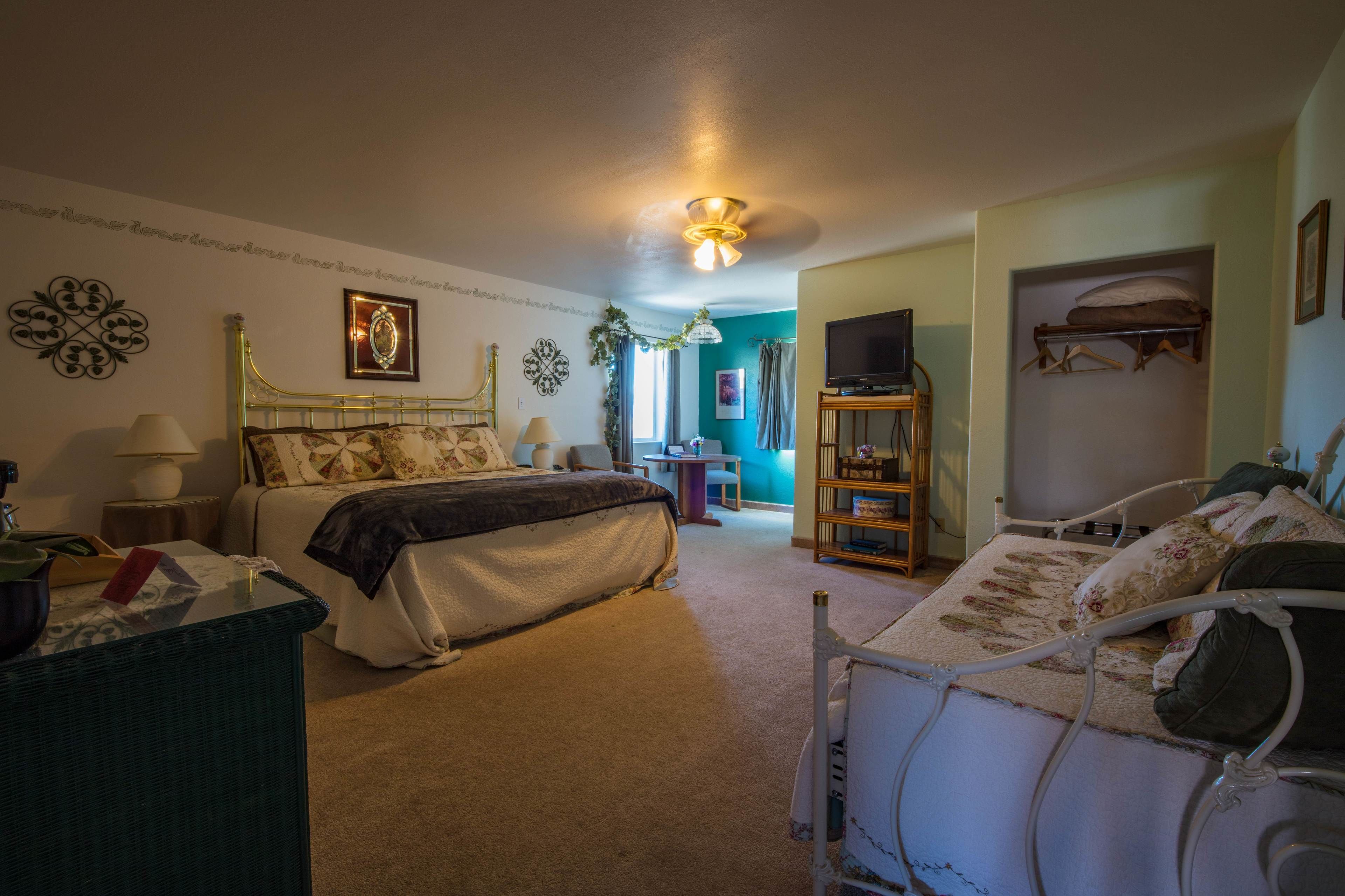 A bedroom with a bed, bedside table, lamp, and a television.