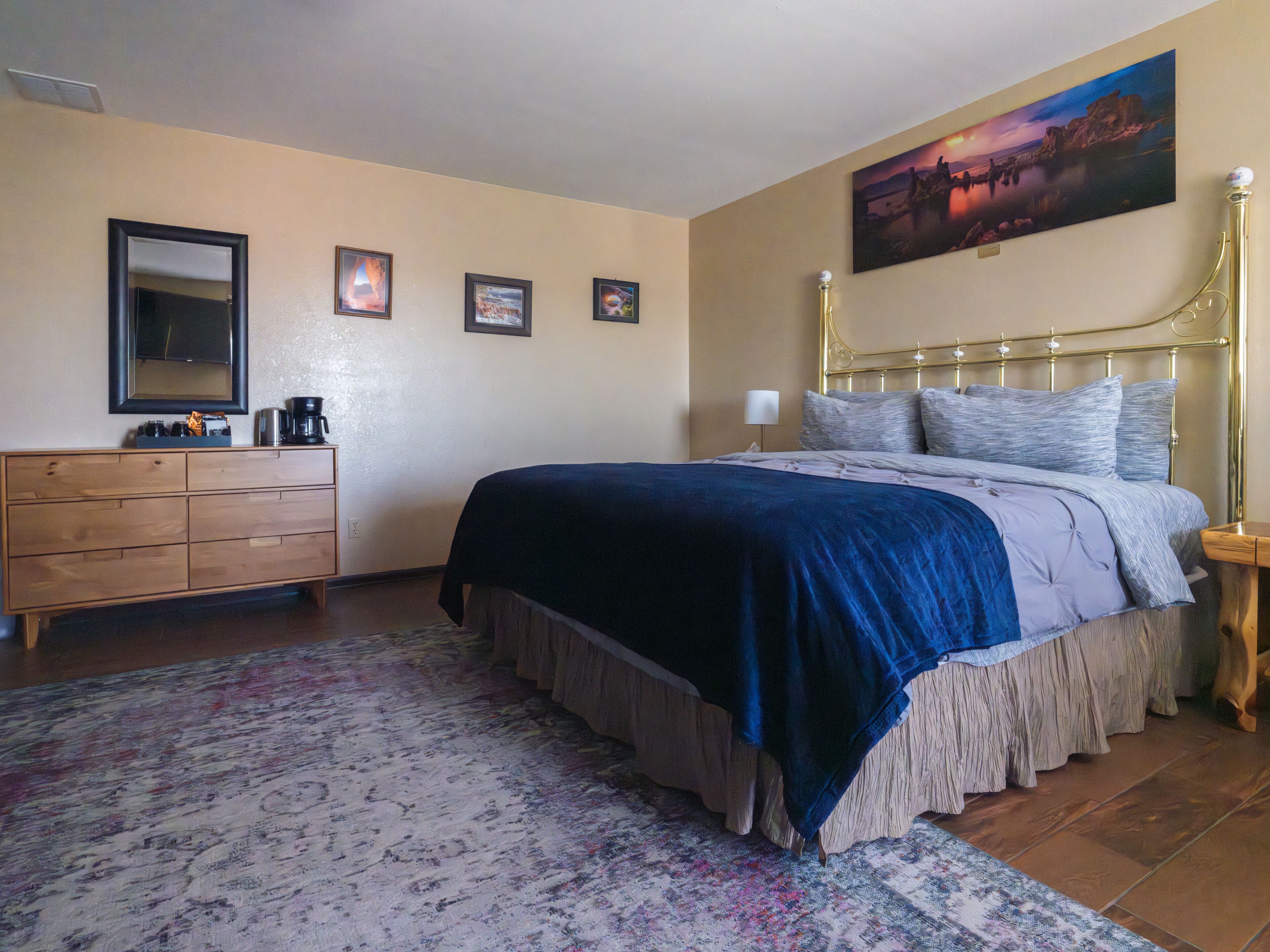 A bedroom with a bed, dresser, and a painting on the wall.
