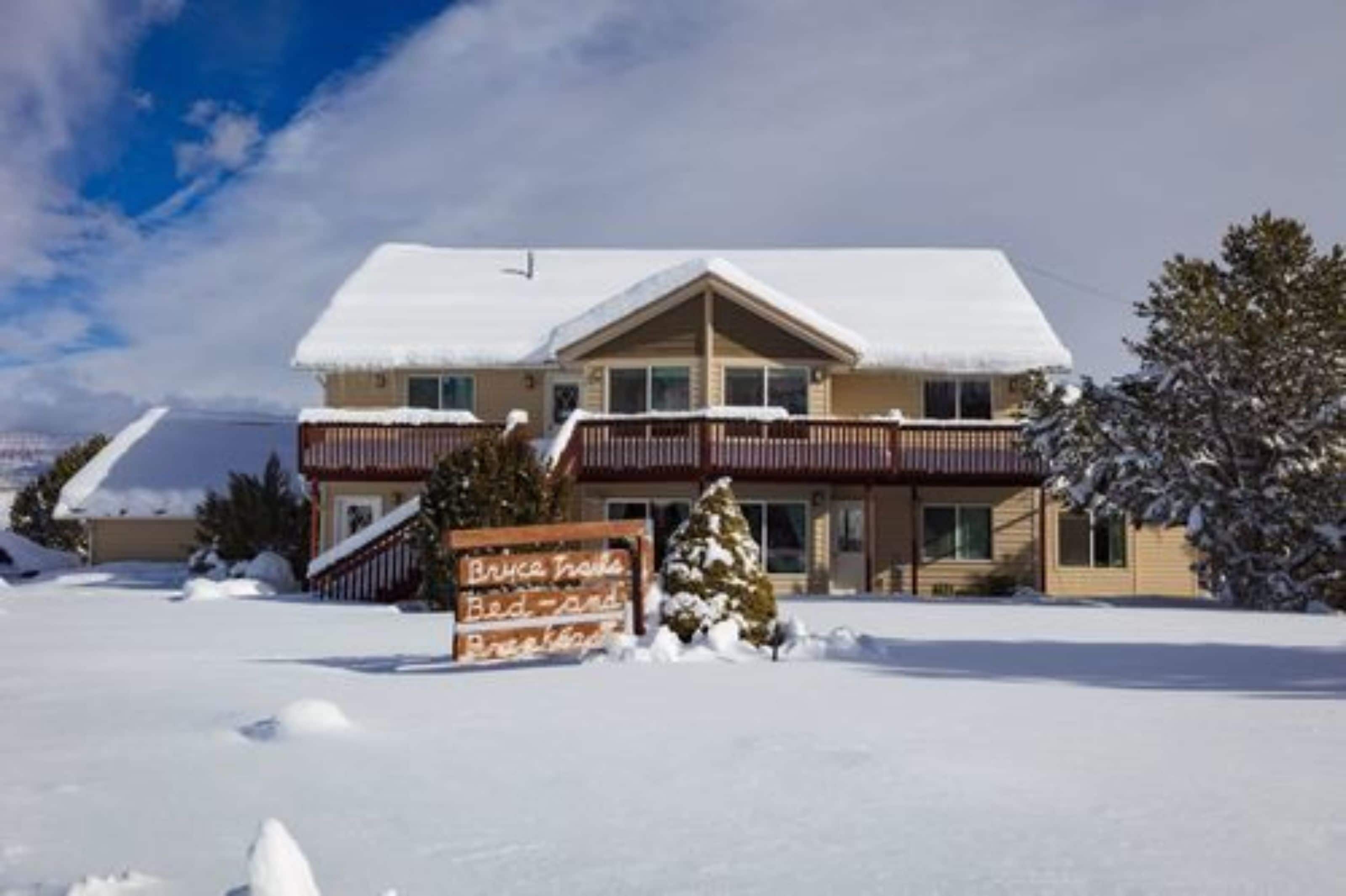 A two-story building with a snow-covered roof and a signboard in front.