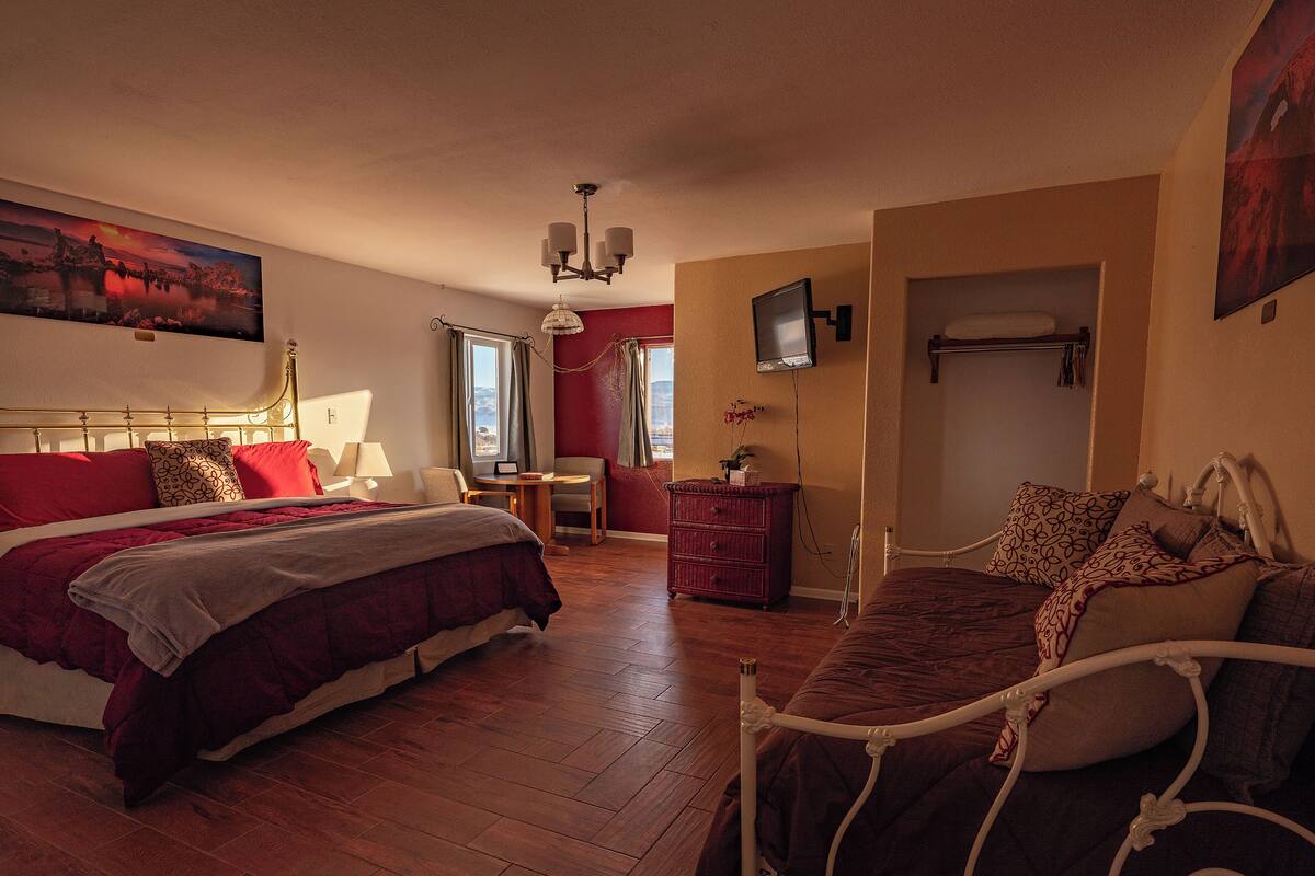 Una habitación de hotel con una cama, un escritorio, una silla, un aparador y un televisor.
