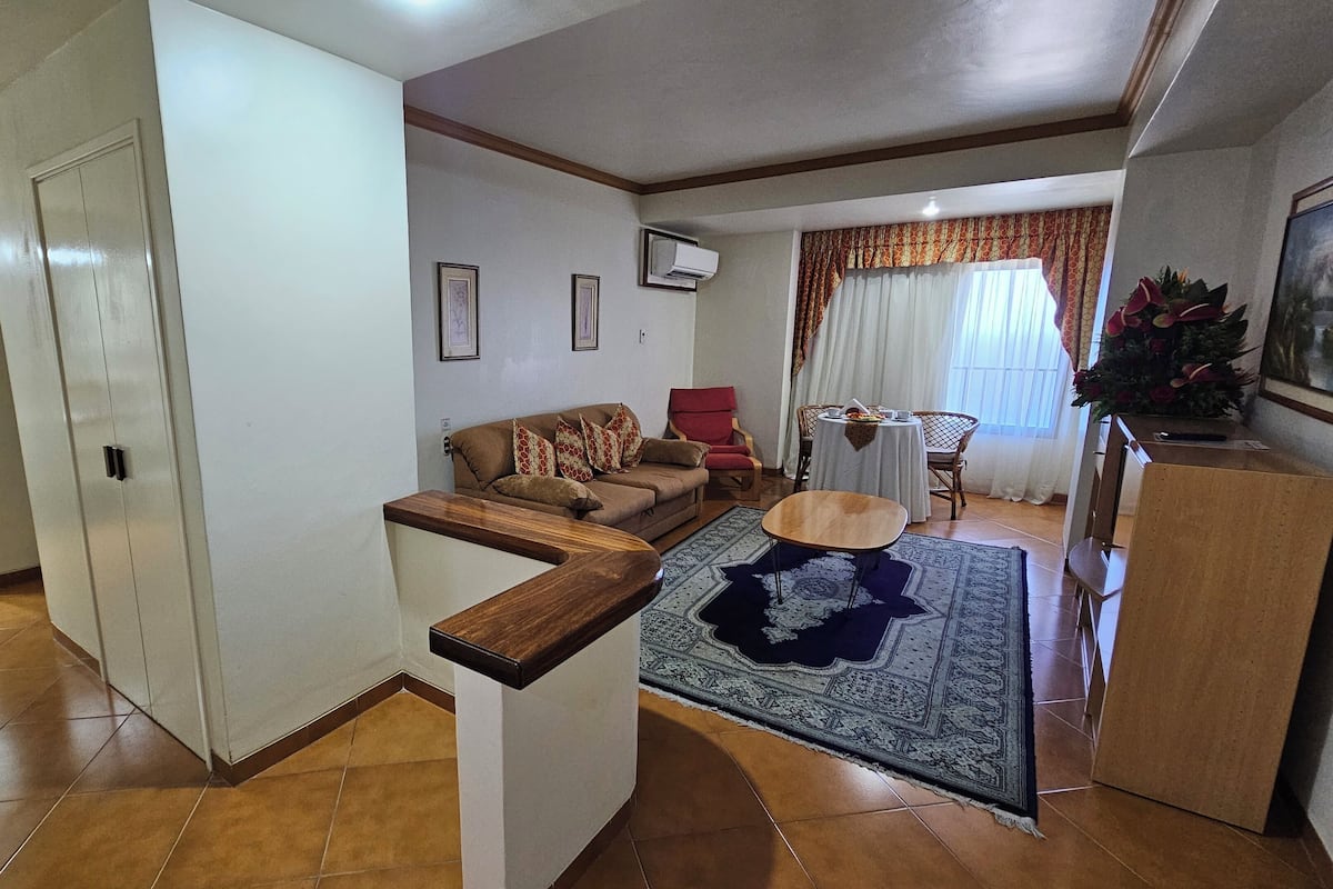 A living room with a sofa, a coffee table, and a dining area with a table and chairs.