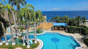 A swimming pool with a circular design, surrounded by palm trees and lounge chairs. - Hotel Ole Caribe (Macuto)