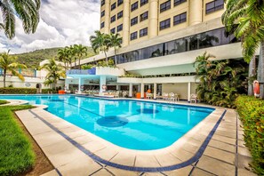 Una piscina al aire libre, sombrillas, sillones reclinables de piscina