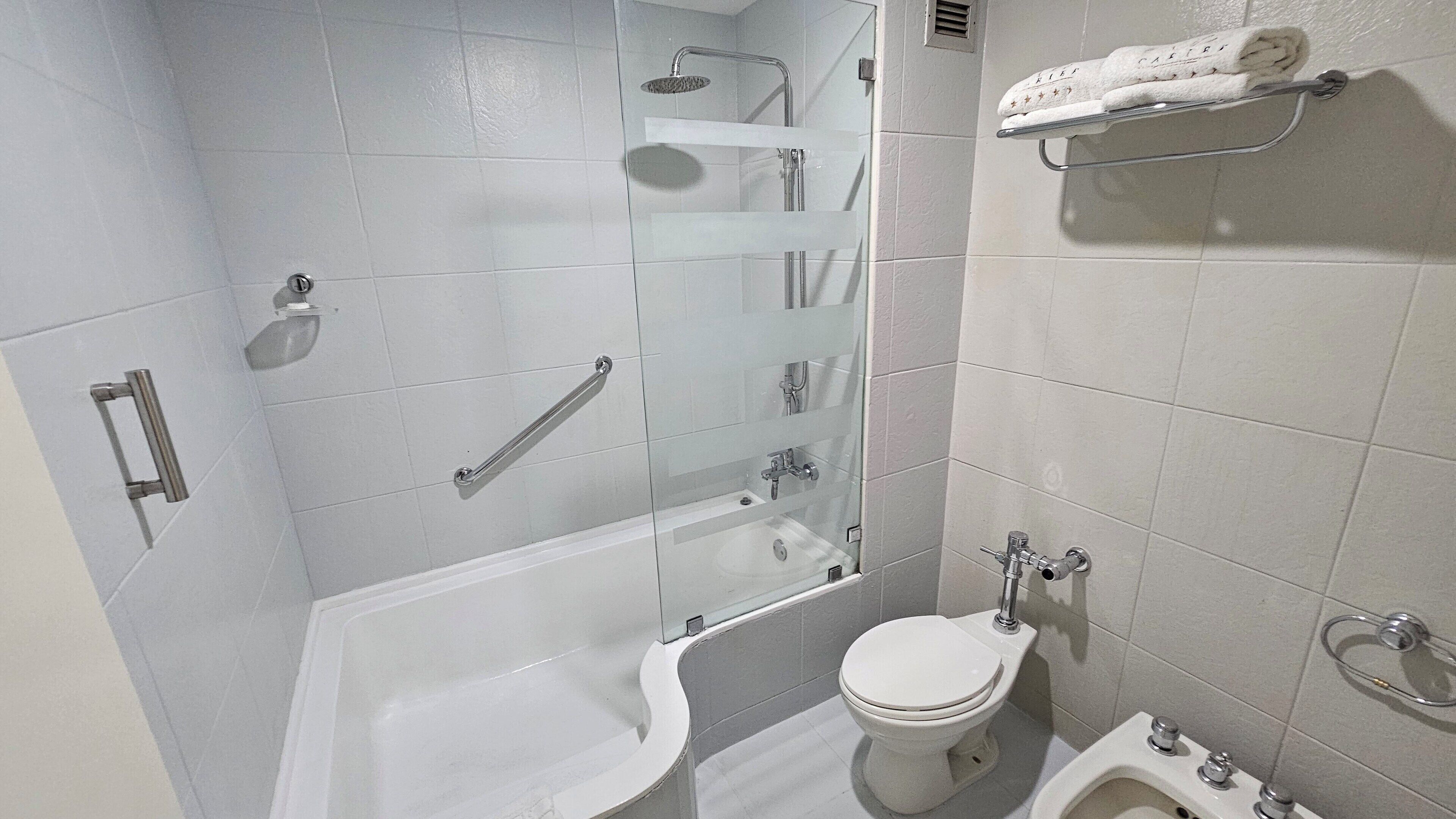 Une salle de bain moderne dotée d’une douche à parois de verre, d’une baignoire, de toilettes et d’un bidet.