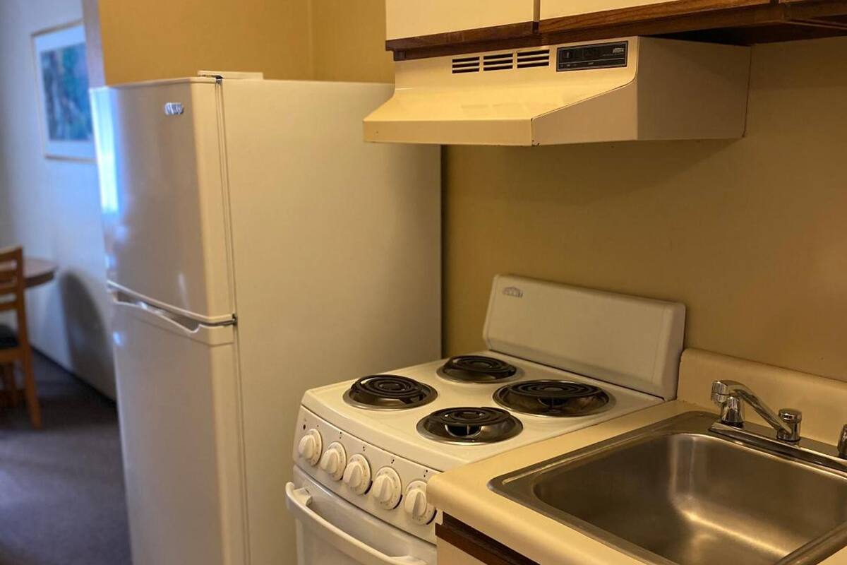 A compact kitchen with a refrigerator, stove, oven, and sink.