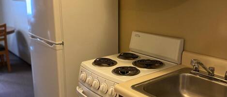 A compact kitchen with a refrigerator, stove, oven, and sink.