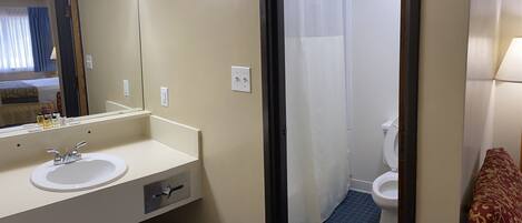 Une salle de bain d’hôtel équipée d’un lavabo, d’un miroir, de toilettes et d’un rideau de douche.