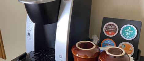 A Keurig coffee maker with a coffee pod holder and two coffee pots on a countertop.