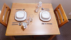 Una mesa de comedor de madera dispuesta con platos, cubiertos y vasos.
