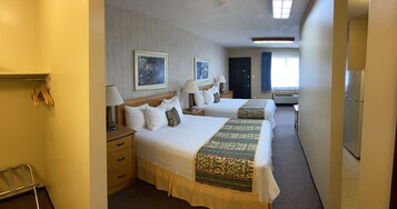 A hotel room with two beds, a desk, a chair, a wardrobe, and a window with curtains.