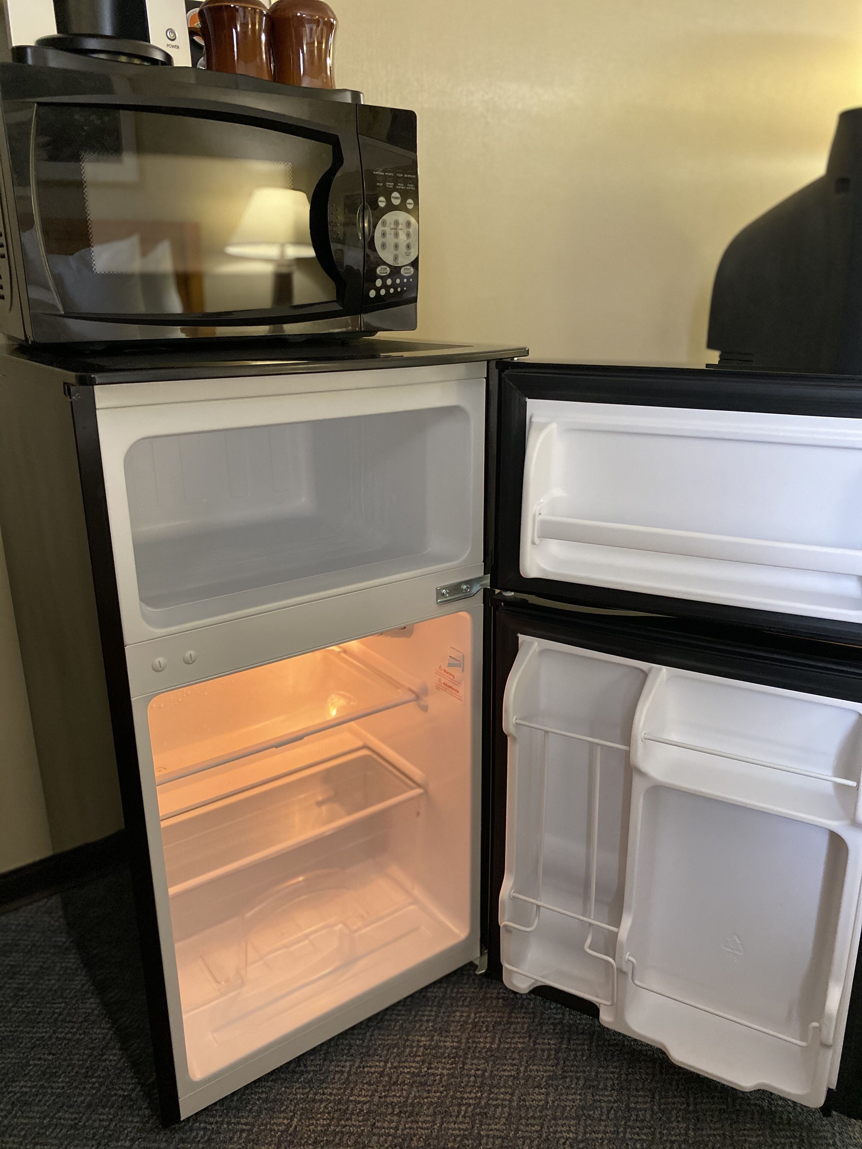 A compact refrigerator with a microwave on top, a freezer compartment, and a main storage area.