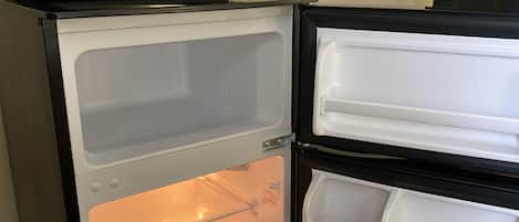 A compact refrigerator with a microwave on top, a freezer compartment, and a main storage area.