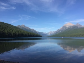 Un lago tranquilo con montañas al fondo y cielo despejado.