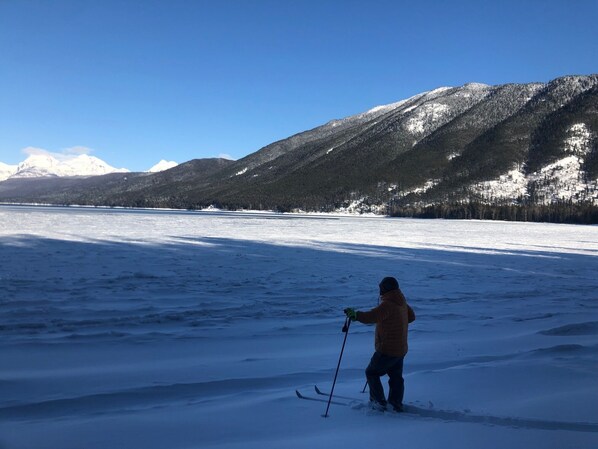 Una persona esquiando sobre un lago helado, con montañas al fondo.