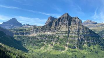 A mountainous landscape with a prominent peak, lush green valleys, and a clear sky.
