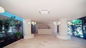A spacious lobby with a reception desk, large windows, and indoor plants. -  Loa Tolú by Bernalo Hotels (Tolú)