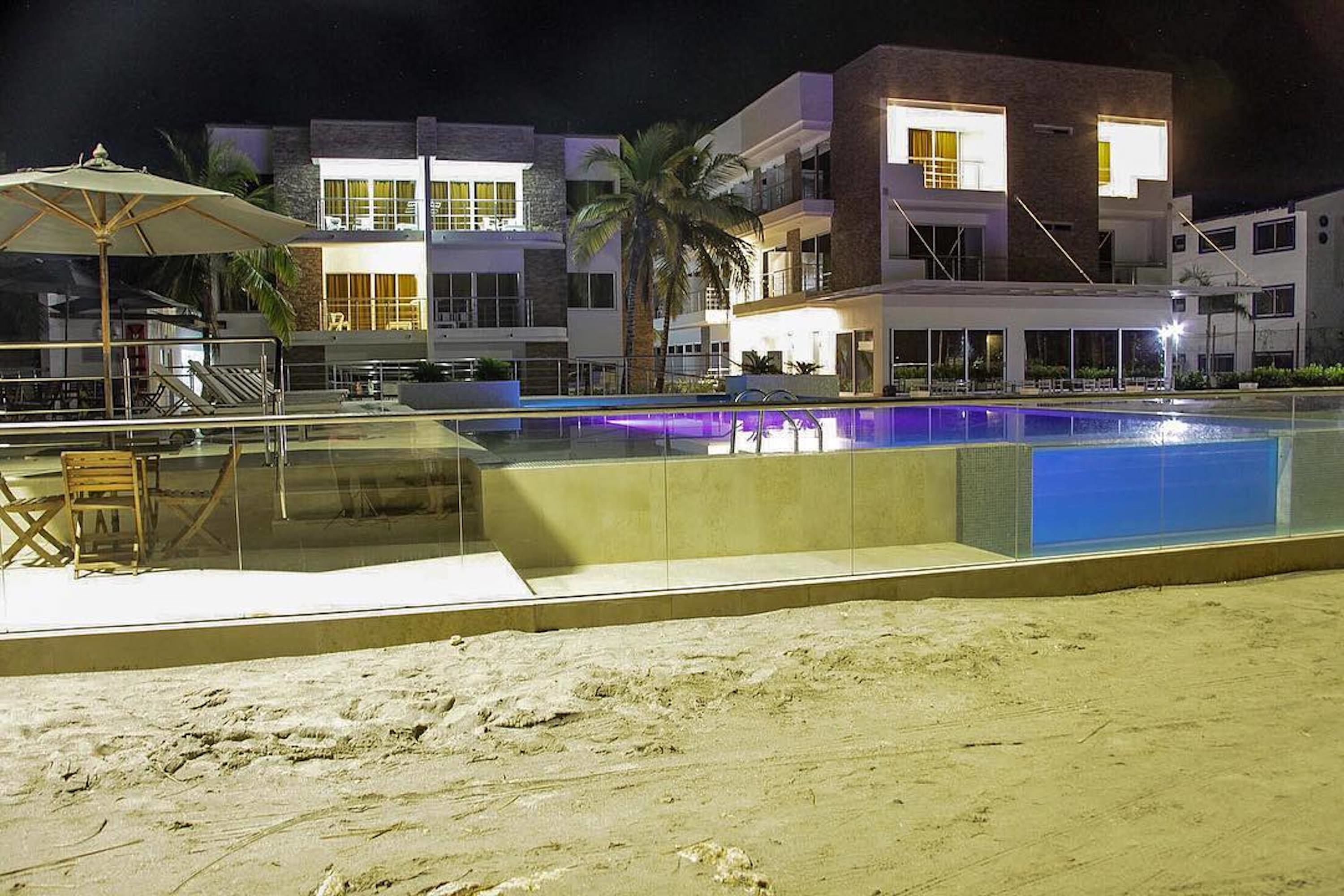 A modern hotel with a swimming pool, outdoor seating, and a beach area.