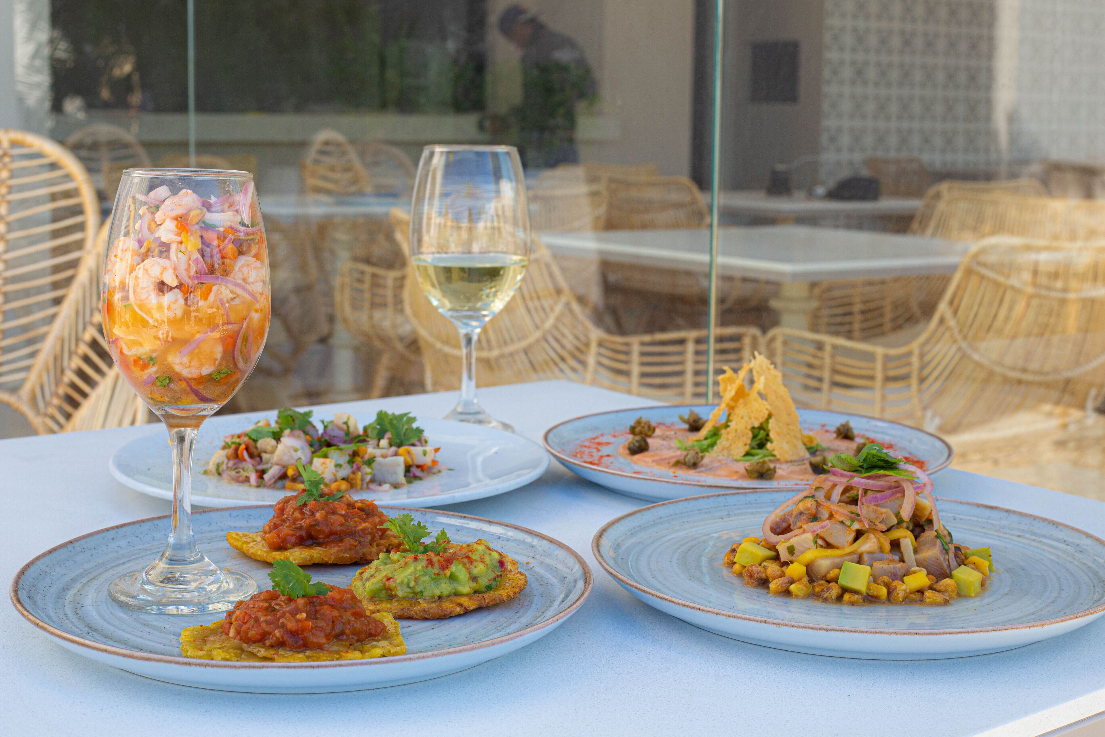 A table with plates of food and two glasses of wine.