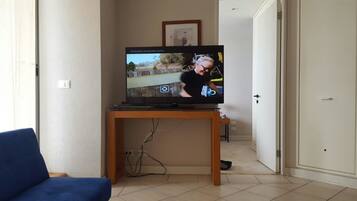 Apartamento família, 2 quartos, vista para a piscina | Sala de estar | TV de tela plana 50 polegadas com canais a cabo, TV