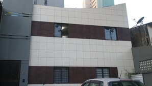 A modern building with a white and brown facade, multiple windows, and a satellite dish on the roof. - Studio Boa Viagem (Recife)