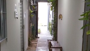 A narrow hallway with a bench, a door, and a light fixture. - Studio Boa Viagem (Recife)