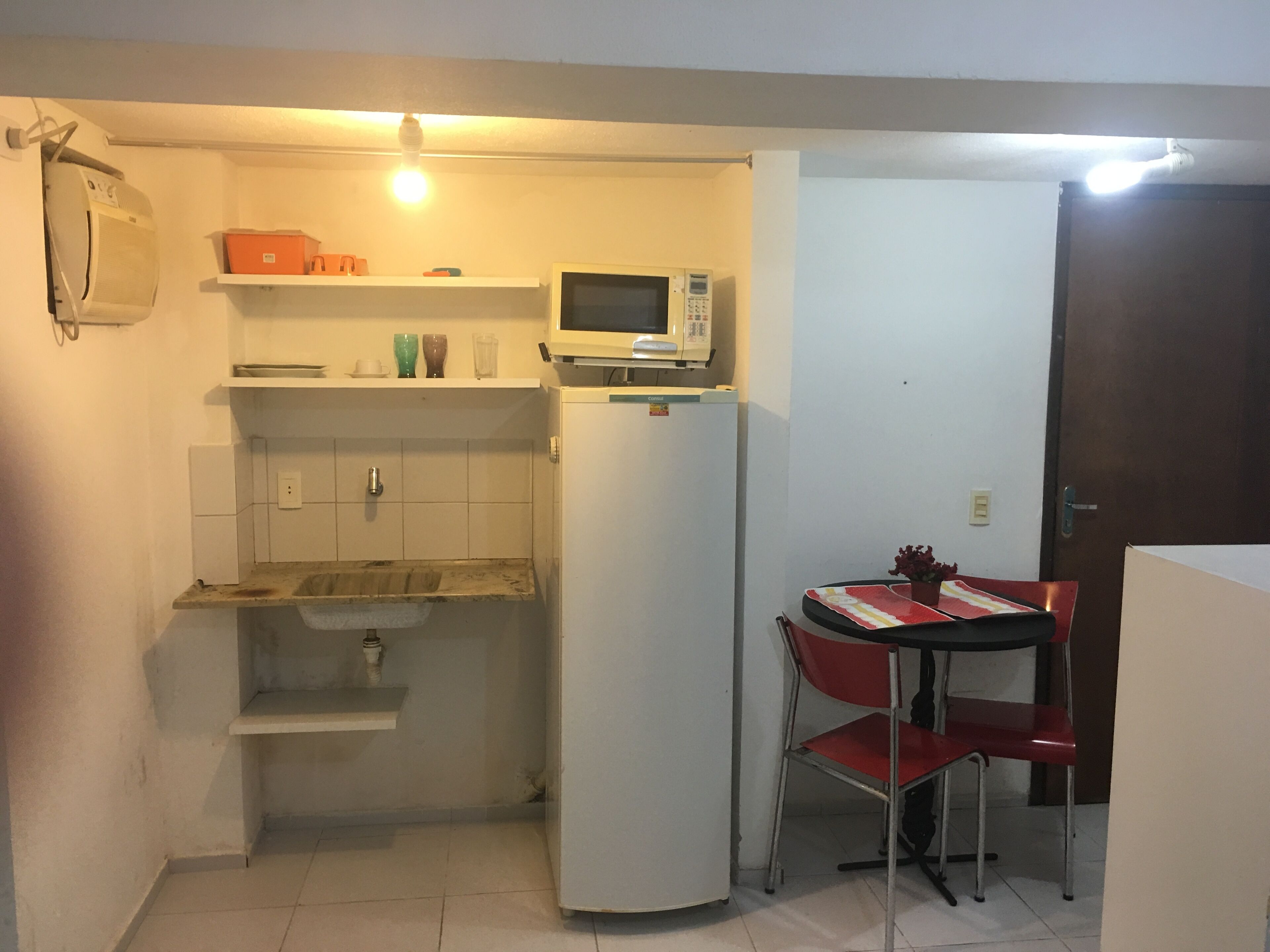 Une cuisine compacte équipée d’un four à micro-ondes, d’un petit réfrigérateur, d’un évier et d’un coin repas avec une table et des chaises.