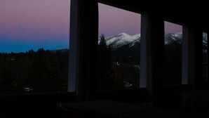 A room with large windows overlooking a snowy mountain range. - Hosteria Pajaro Azul (San Carlos de Bariloche)