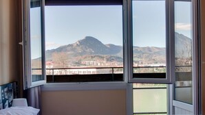 A hotel room with a large bed, a view of mountains, and a balcony. - Hotel San Blas (Abadino)