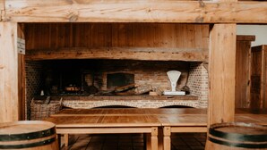 A rustic wooden interior with a brick fireplace, a wooden table, and two barrels.