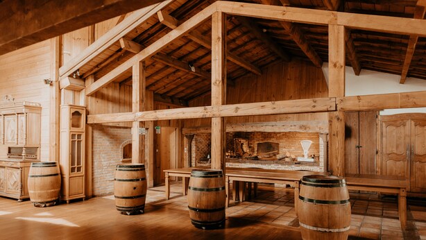 A rustic wooden interior with high ceilings, wooden beams, and a brick fireplace.