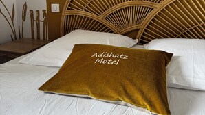 A bed with a headboard, a wall with a mural, and a pillow with text.