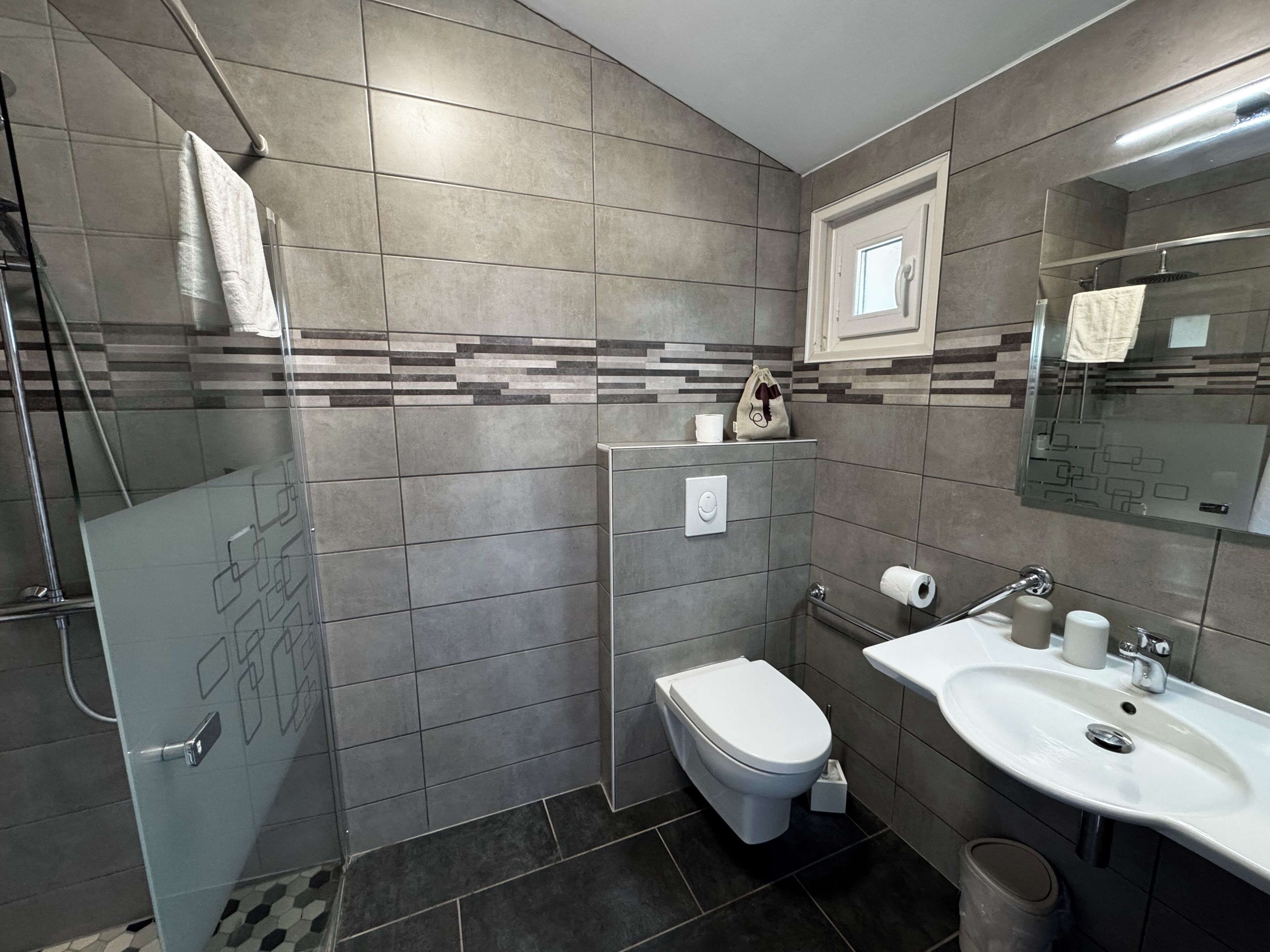 A modern bathroom with a shower, toilet, and sink.