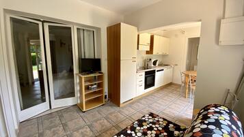 A compact living space with a kitchenette, a television on a stand, and a dining area with a table and chairs.