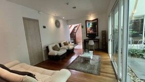 A spacious living room with a sofa set, a coffee table, and a TV. There is a staircase leading to an upper level. - Casa Hotel Boyaca Real (Bogotá)