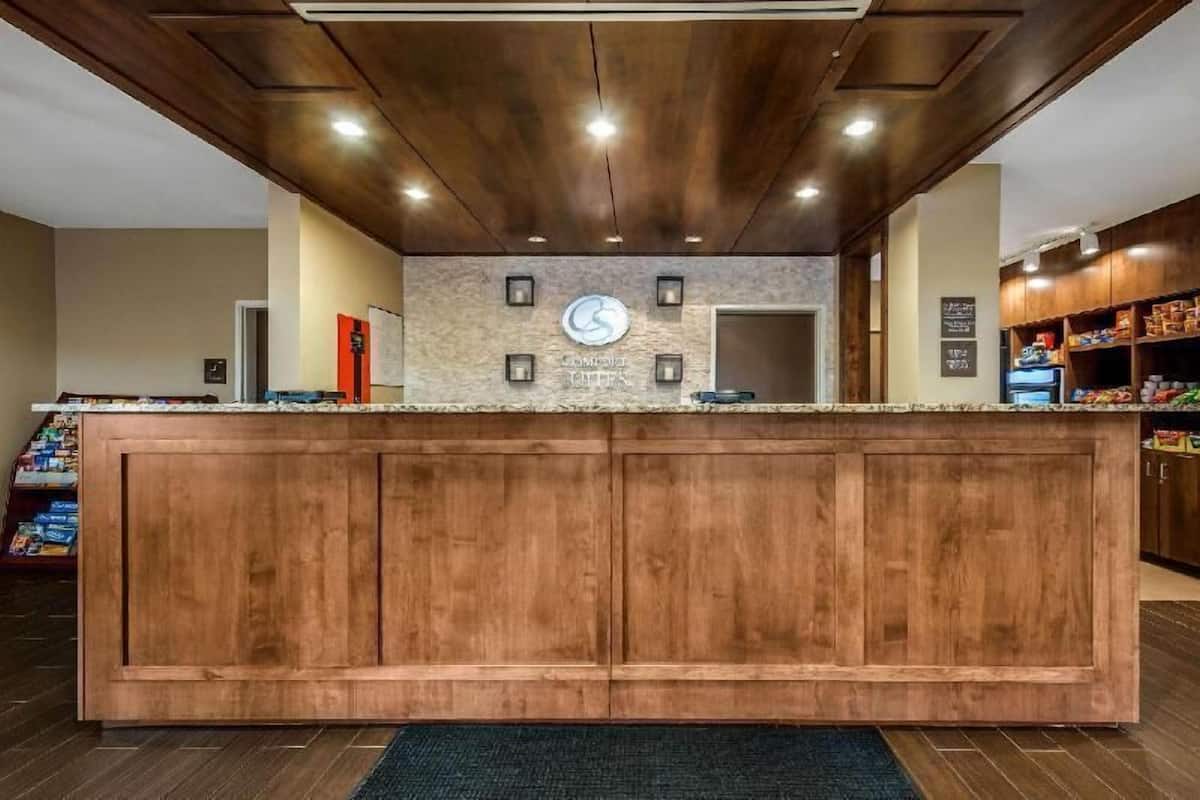 Un espace d’accueil avec un comptoir en bois, une horloge et un panneau fixé au mur.