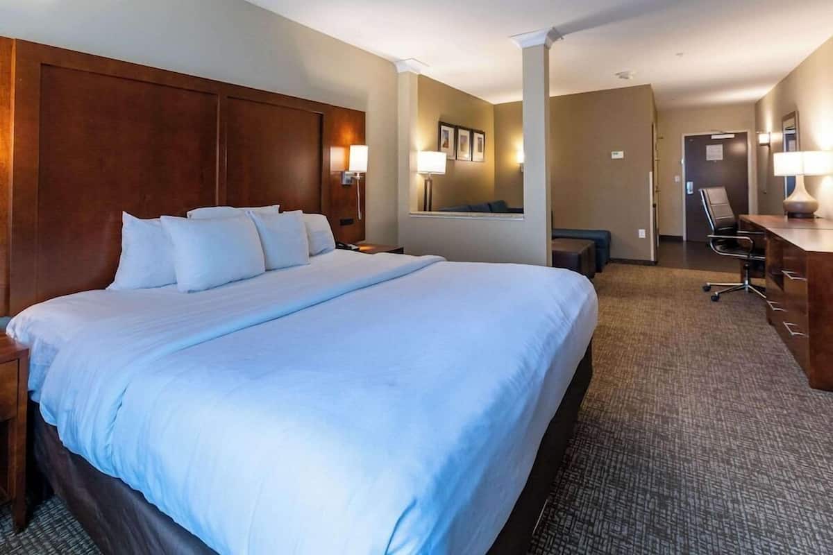 Une chambre d’hôtel avec un grand lit, un bureau, une chaise et un petit coin salon.