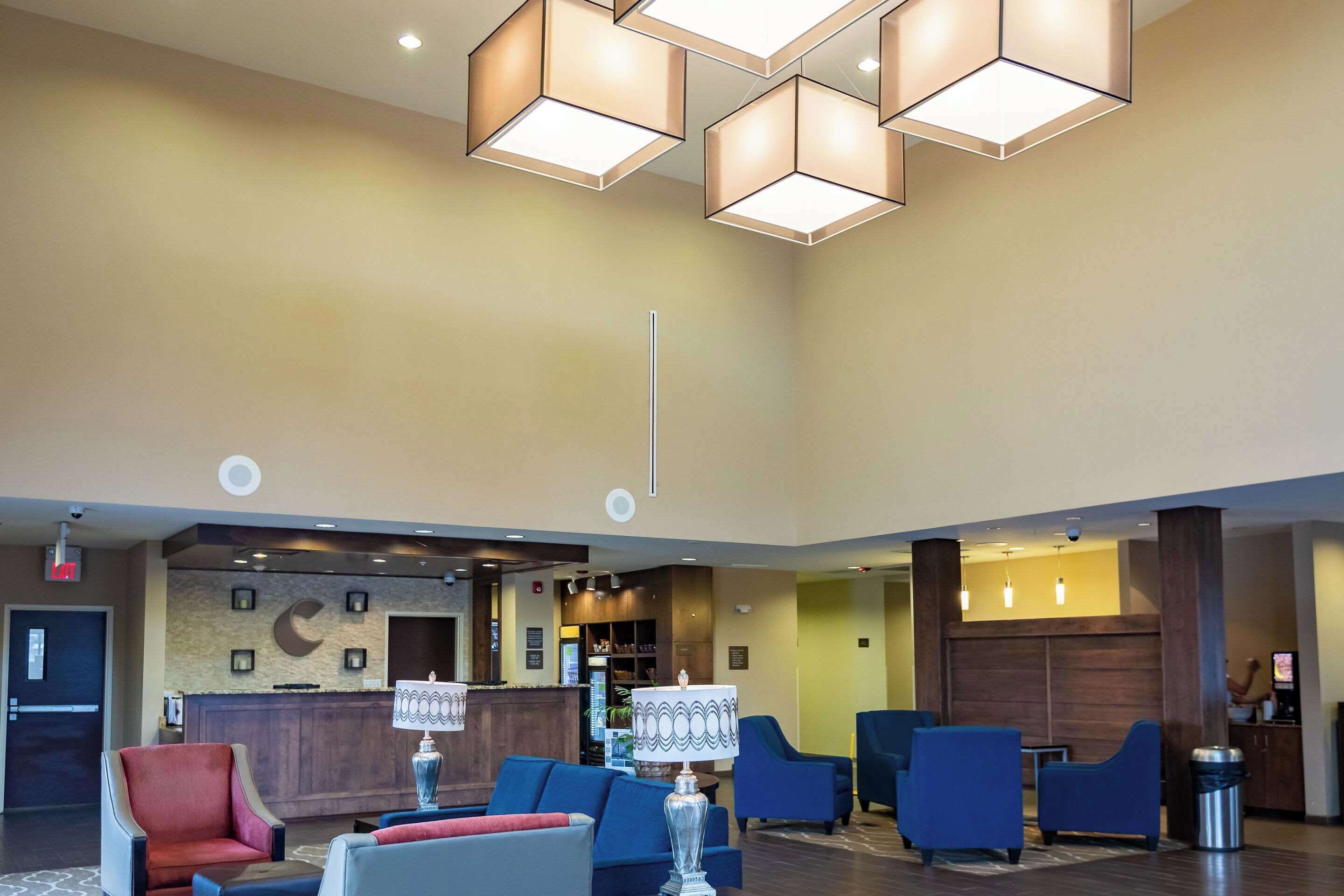 A lobby with a reception desk, blue seating, and modern pendant lighting.