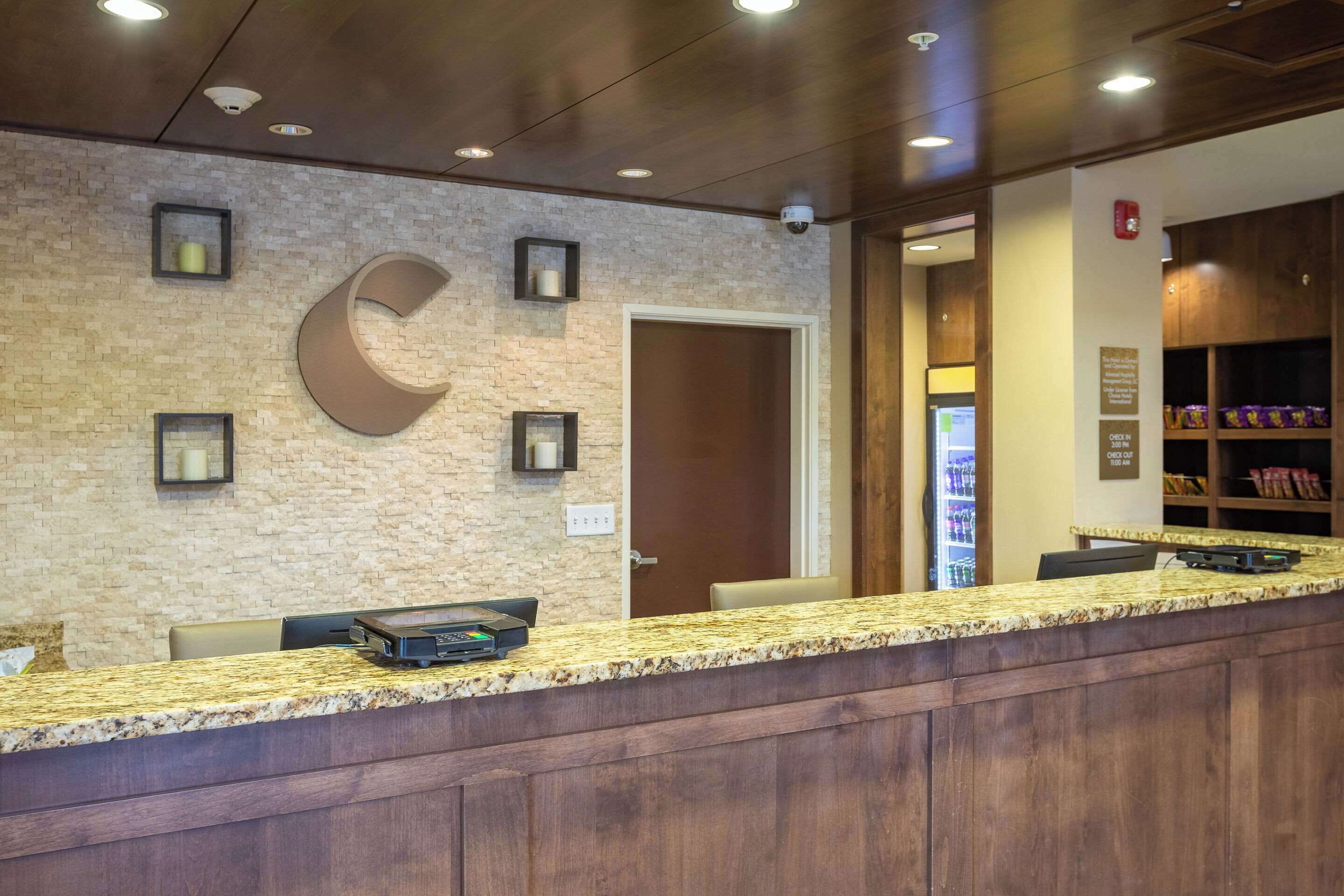 A reception area with a granite counter, a large clock, and a door leading to a room.