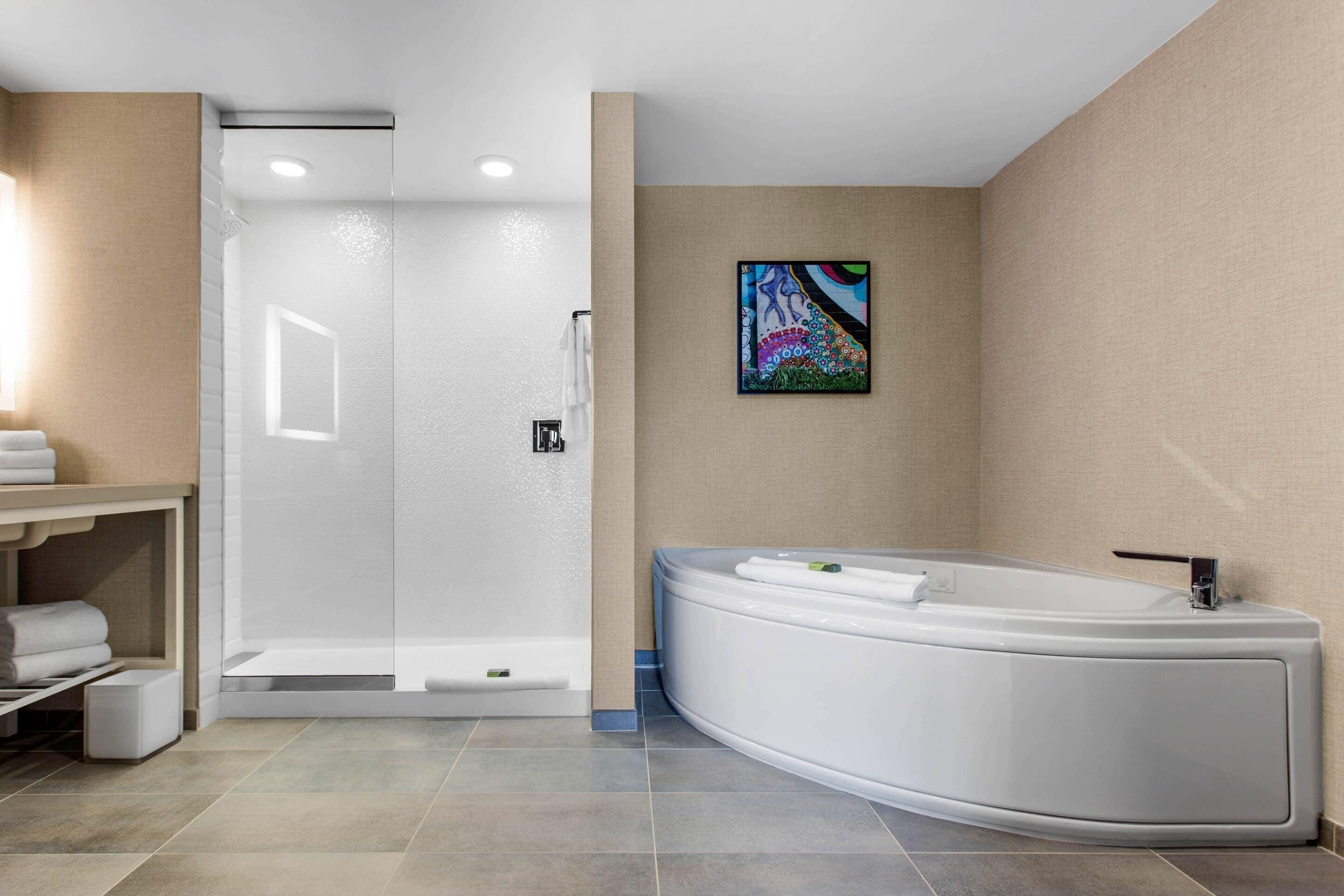 A modern bathroom with a walk-in shower, a freestanding bathtub, and a towel rack.