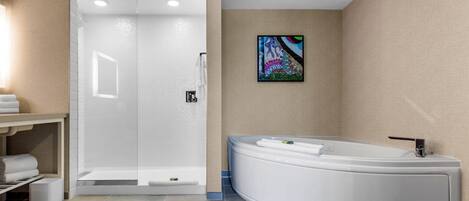 A modern bathroom with a walk-in shower, a freestanding bathtub, and a towel rack.