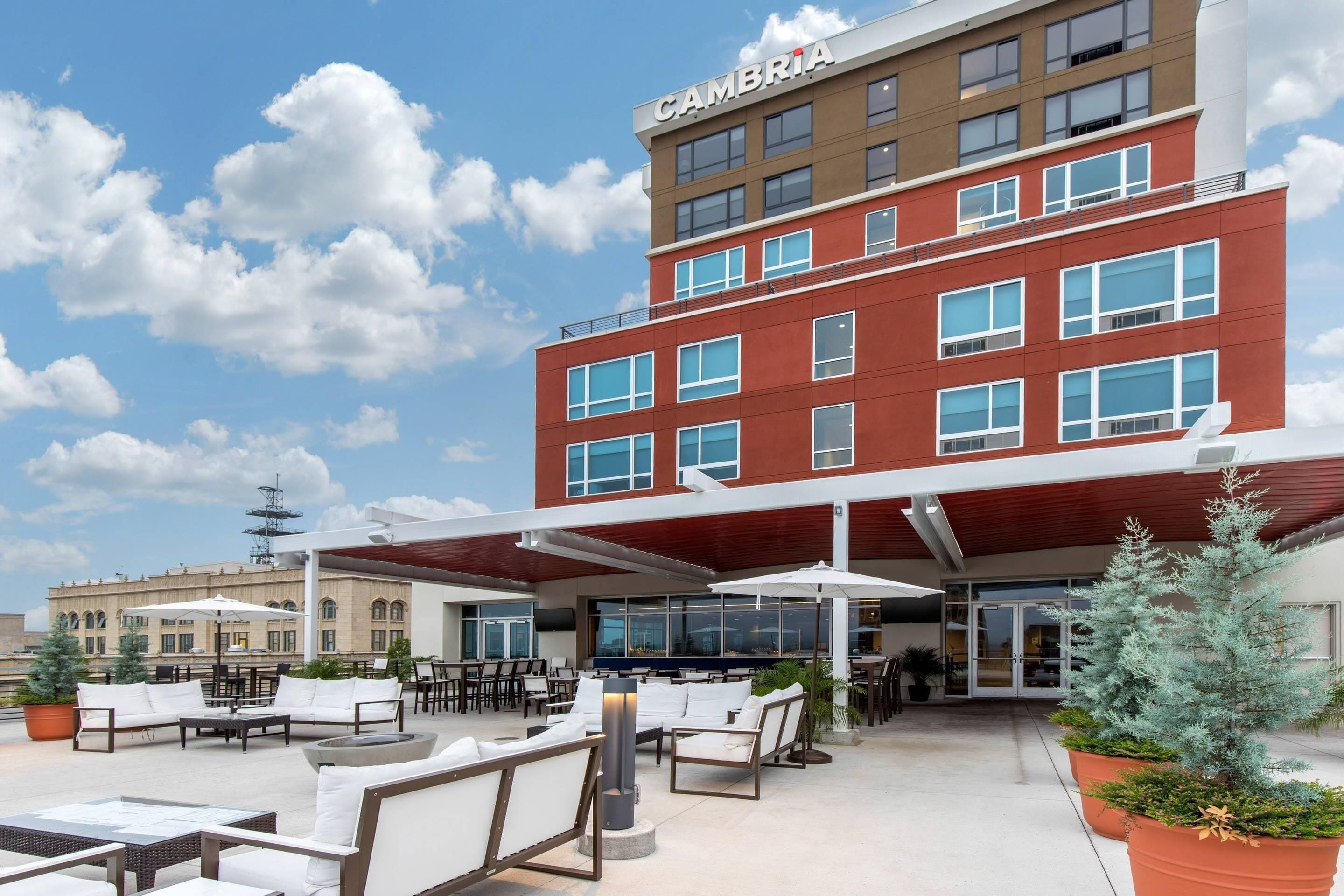 Un hôtel moderne à la façade rouge, doté d’un espace extérieur aménagé et d’une terrasse couverte.