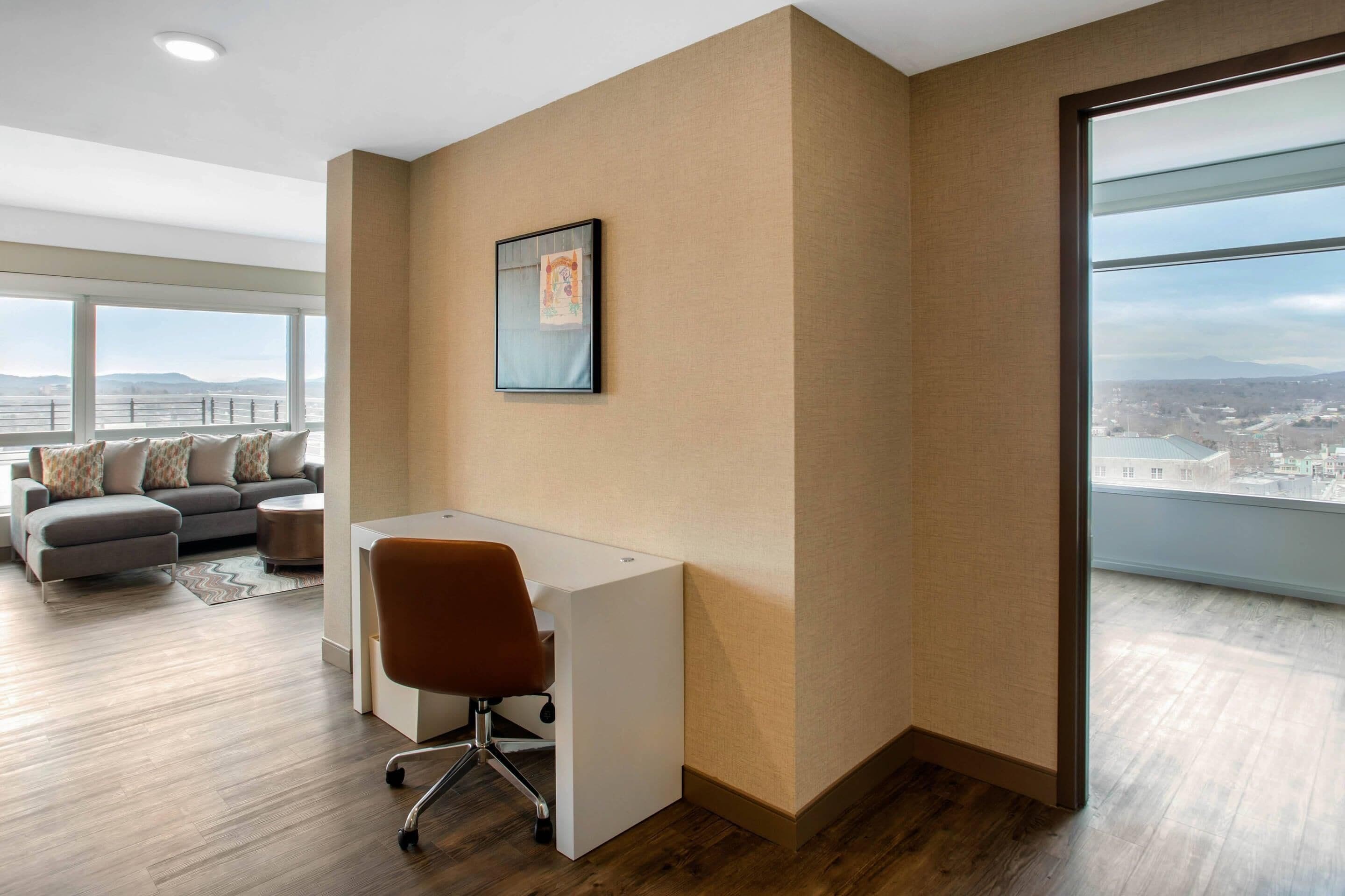 A modern office space with a large desk, a comfortable sofa, and a city view through large windows.