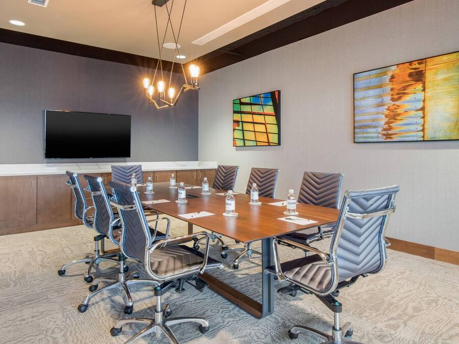 A conference room with a large table, chairs, a flat-screen TV, and artwork on the walls.