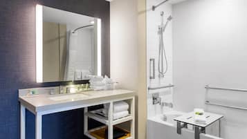 Un bany modern amb un mirall gran, un lavabo, una dutxa i un penjador de tovalloles.