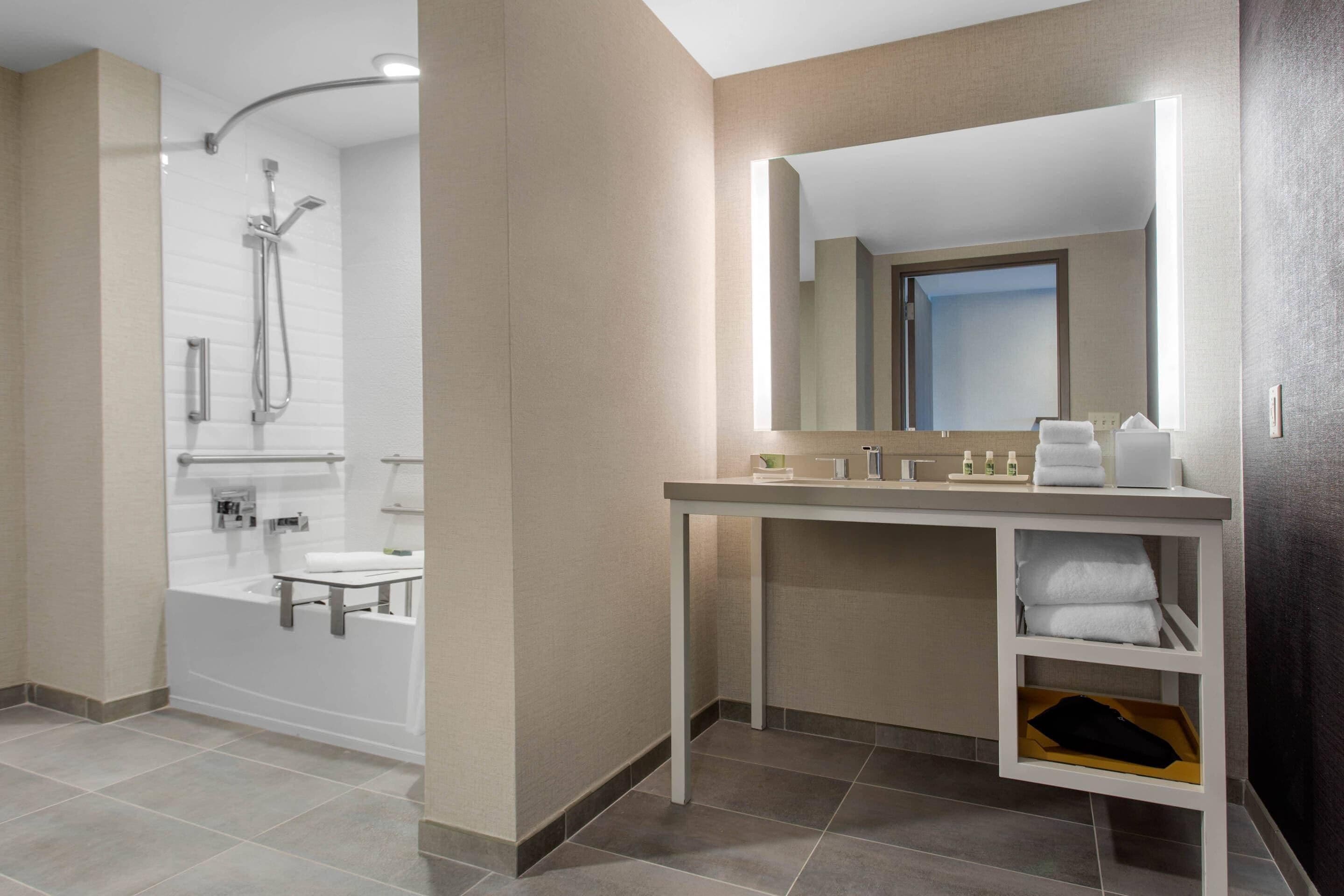 A modern bathroom with a bathtub, a shower, and a vanity with a mirror.
