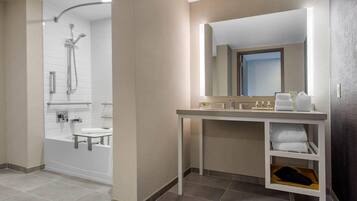 A modern bathroom with a bathtub, a shower, and a vanity with a mirror.