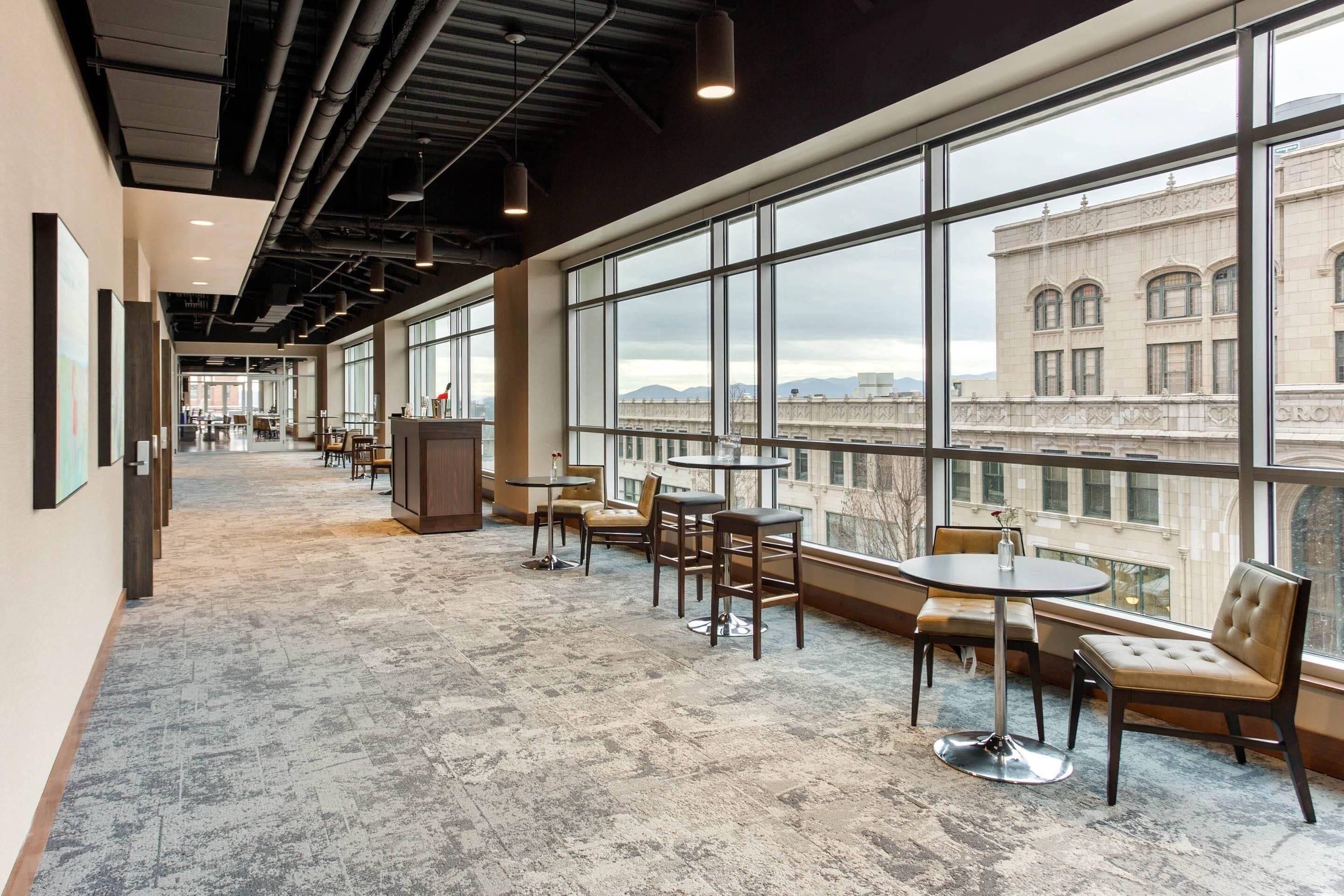 A spacious corridor with large windows, modern furniture, and a view of a historic building.