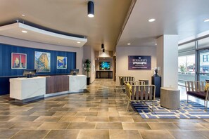 A hotel lobby with a reception desk, seating area, and artwork on the walls. - Cambria Hotel Downtown Asheville (Asheville)