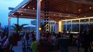 An outdoor dining area with tables and chairs, surrounded by potted plants and string lights. - Cambria Hotel Downtown Asheville (Asheville)