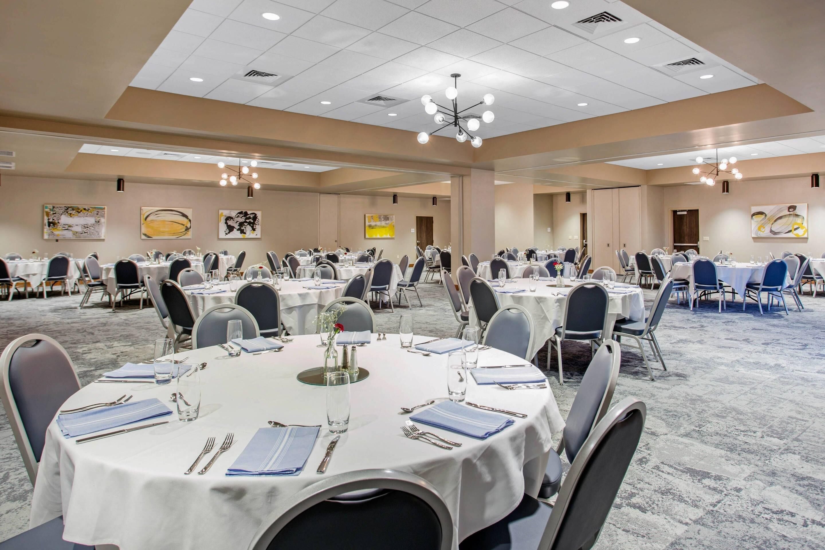 A large conference room with round tables, chairs, and a carpeted floor.